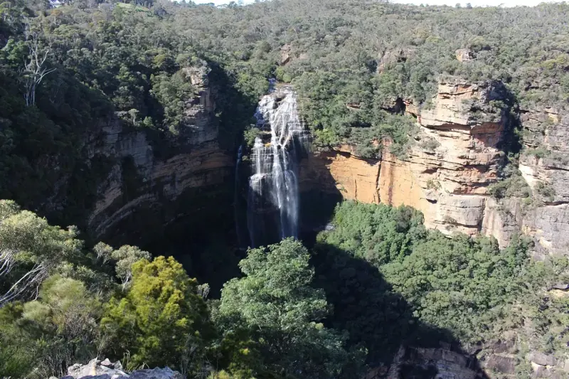 Waterfall dropping beside sandstone cliffs
